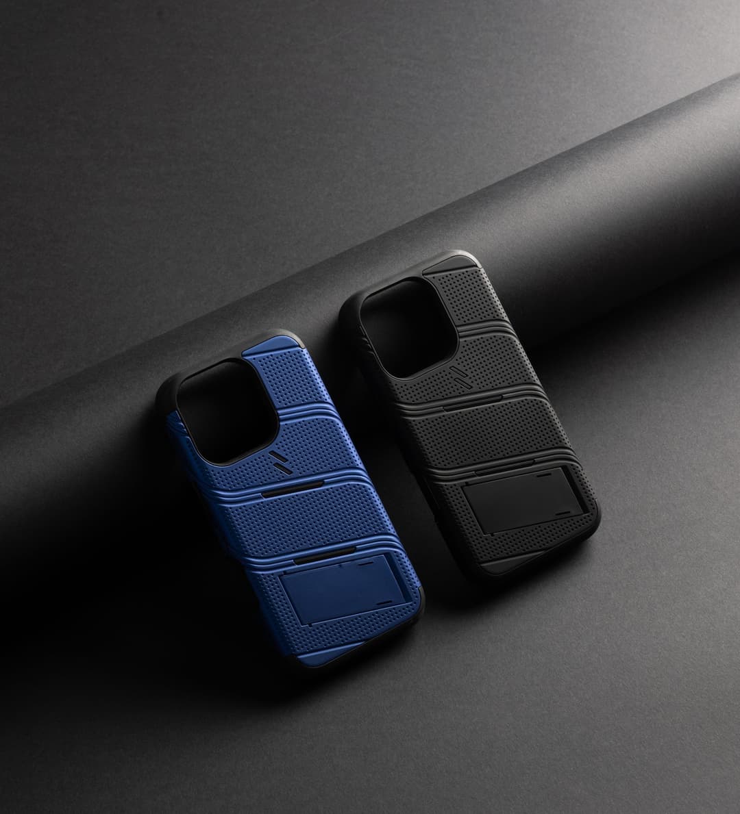 ZIZO Bolt rugged phone case duo — navy blue and black, dot-grip texture with built-in kickstand, on a dark studio backdrop